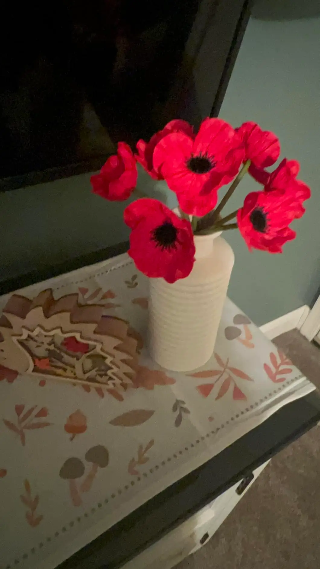 Red anemone poppies in a tall white vase