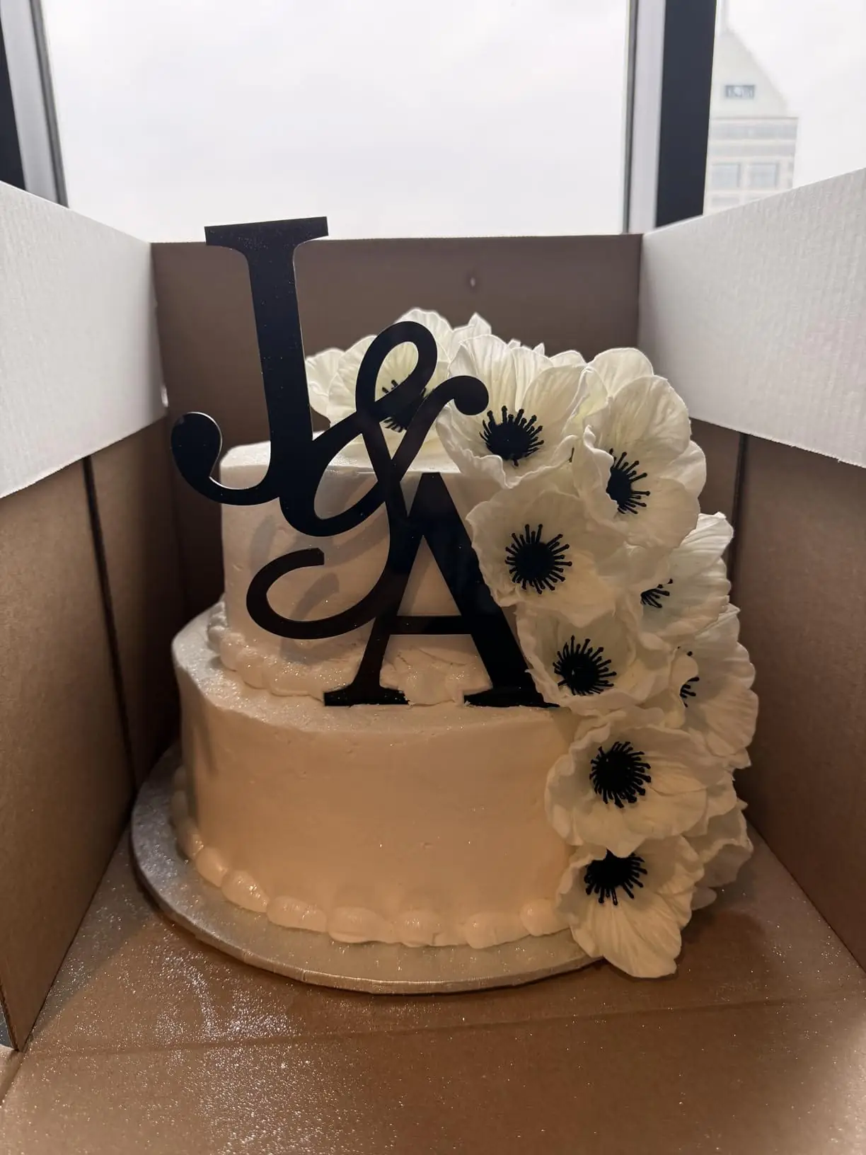 White anemone poppies decorating a wedding cake with a J and A cake topper, customer photo