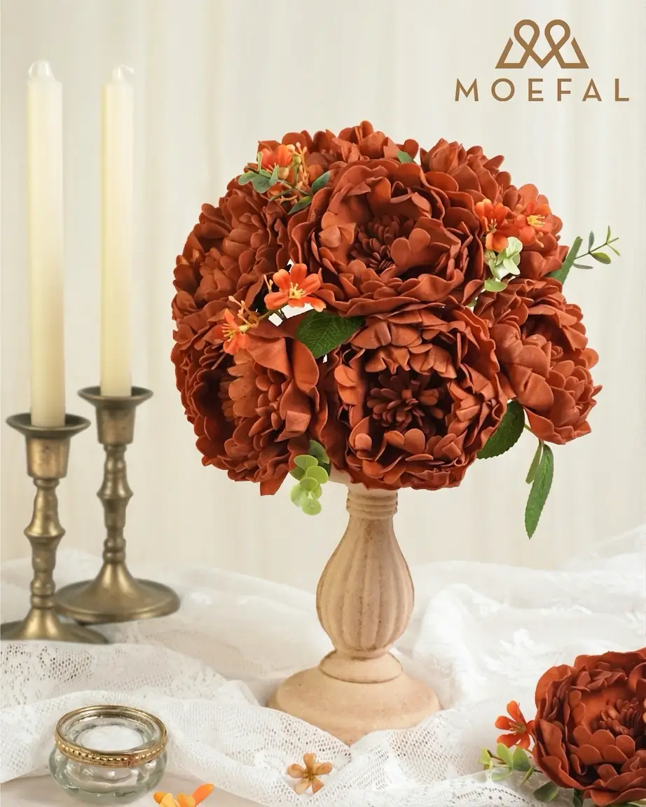 Terracotta burnt-edge artificial peonies as a table centerpiece between taper candles