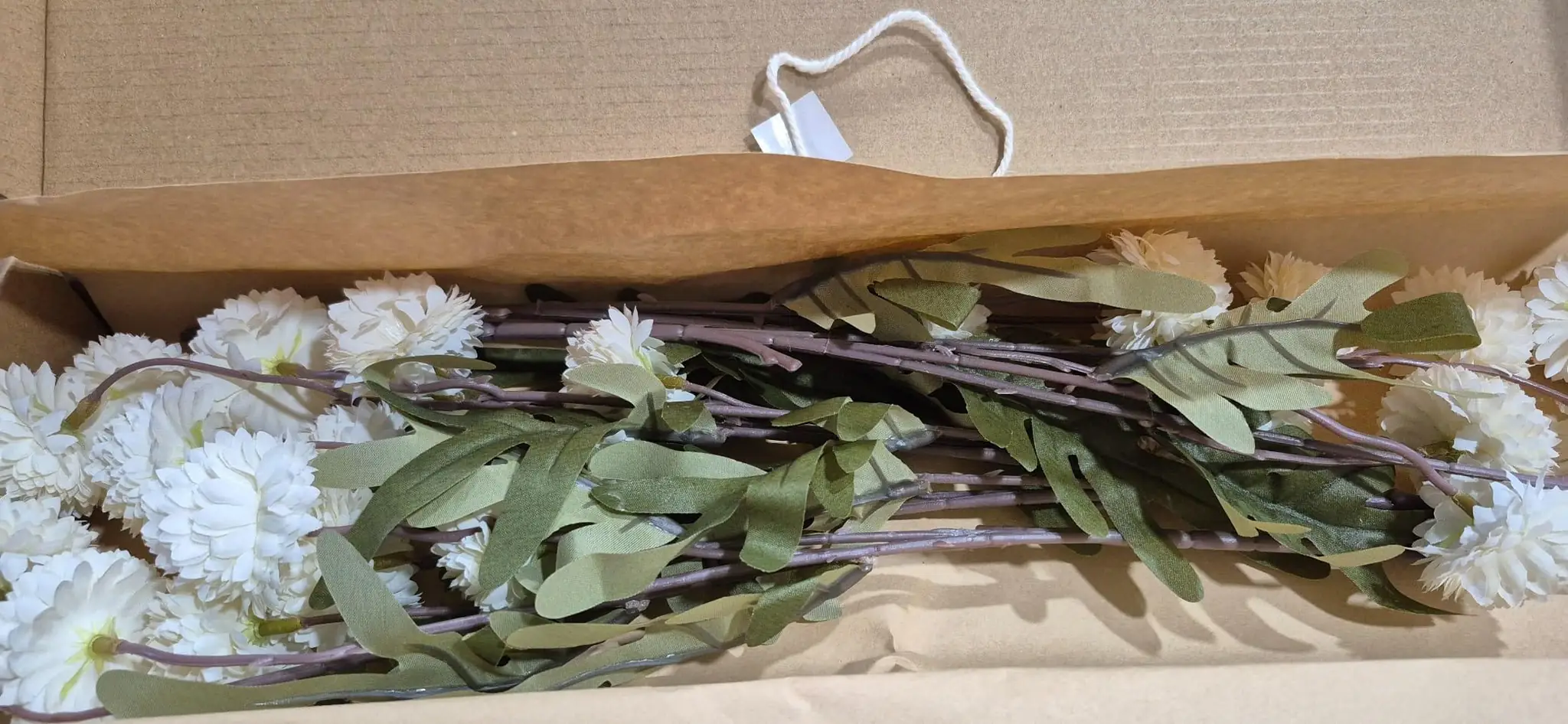 White pompon mum stems in the shipping box on kraft paper