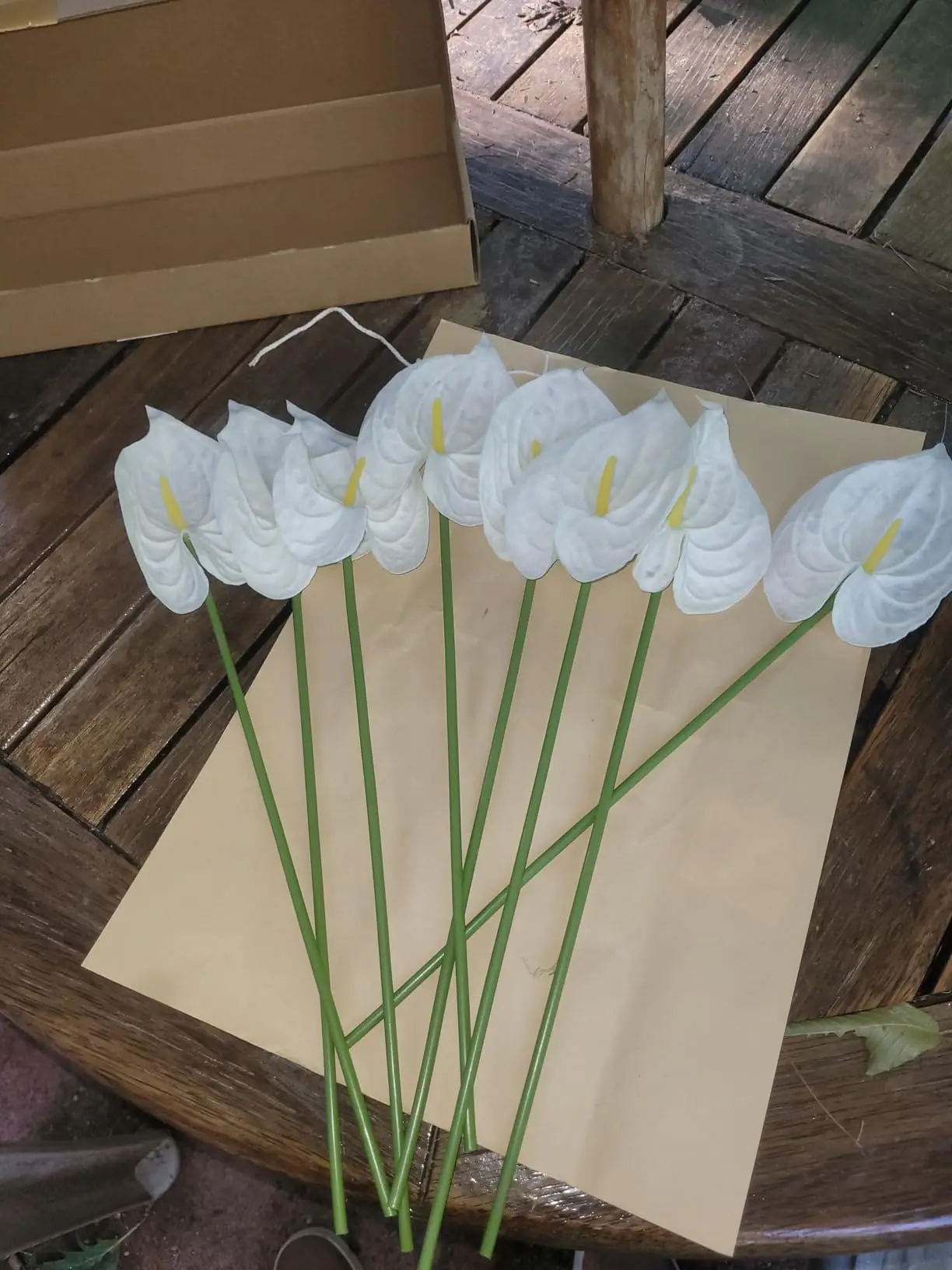 White artificial anthurium stems laid out on kraft paper