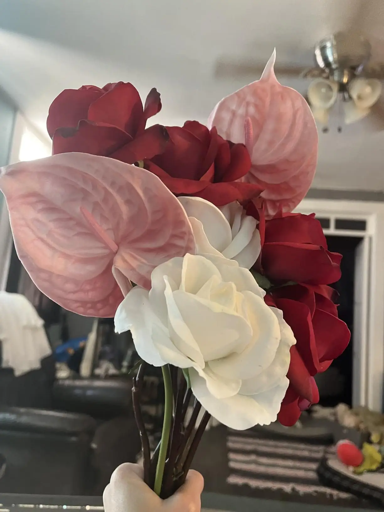 Hand-held bouquet of blush pink anthuriums with red and white roses