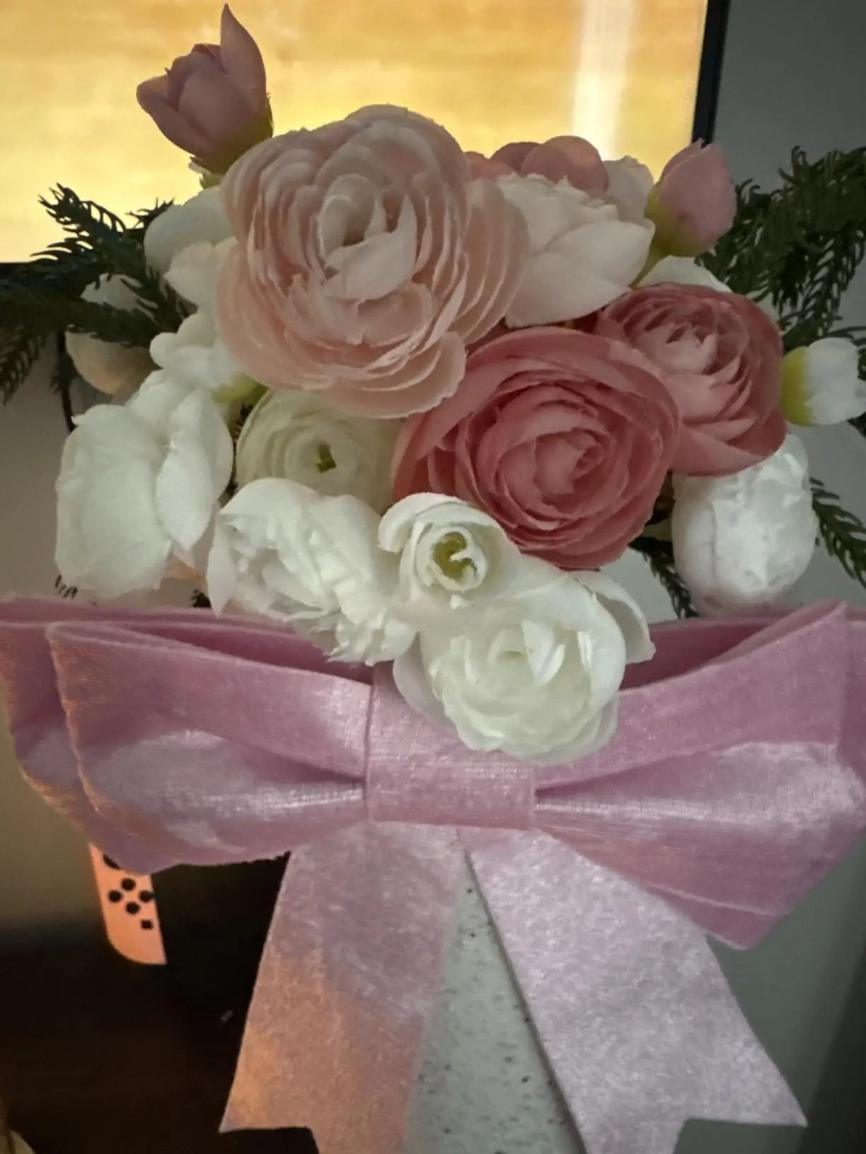 Close-up of a dusty rose and white ranunculus arrangement finished with a pink velvet bow