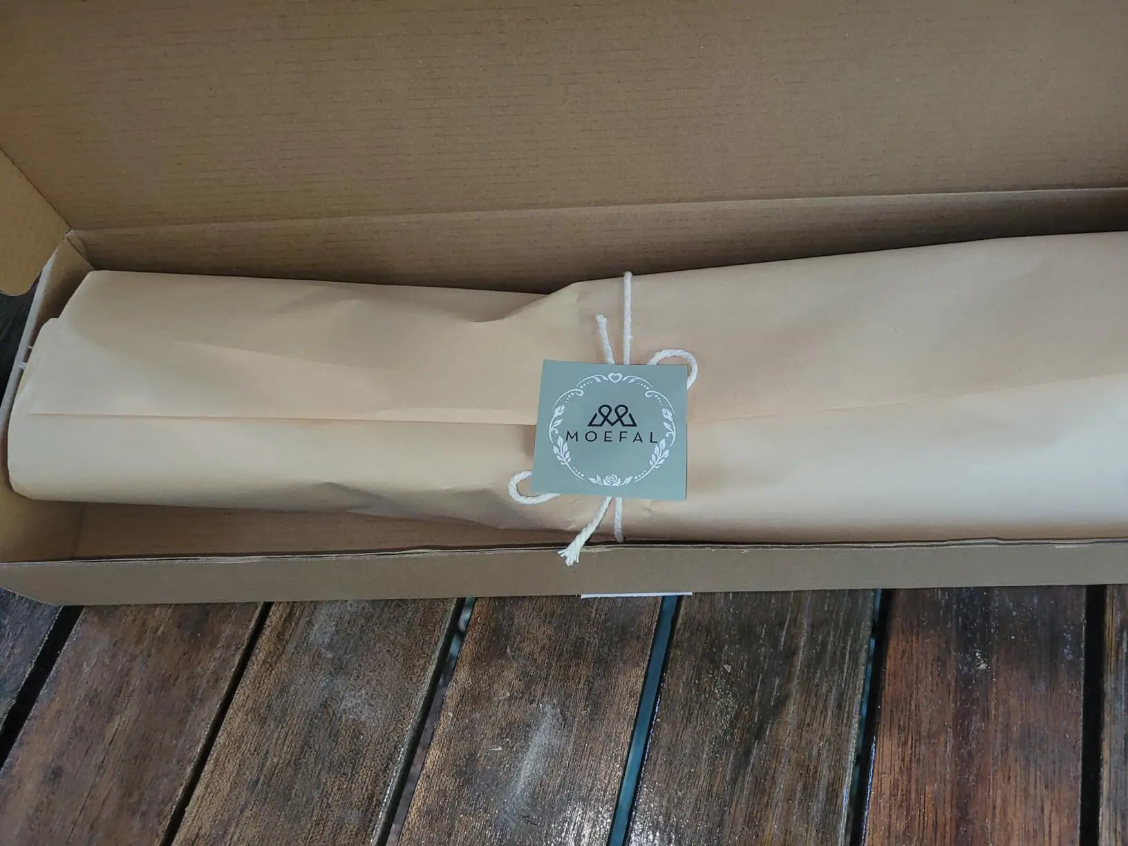 MOEFAL branded kraft wrap and tag in the shipping box on a deck